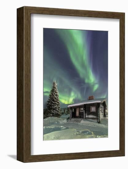 The Northern Lights (Aurora borealis) frame the wooden hut in the snowy woods, Pallas, Yllastunturi-Roberto Moiola-Framed Photographic Print