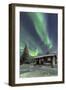 The Northern Lights (Aurora borealis) frame the wooden hut in the snowy woods, Pallas, Yllastunturi-Roberto Moiola-Framed Photographic Print