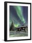 The Northern Lights (Aurora borealis) frame the wooden hut in the snowy woods, Pallas, Yllastunturi-Roberto Moiola-Framed Photographic Print