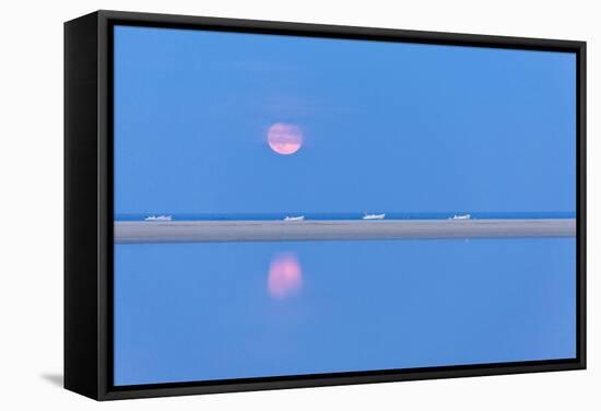 The pink full moon is reflected in the blue water of the Notteri pond, Villasimius, Sardinia, Italy-Roberto Moiola-Framed Stretched Canvas