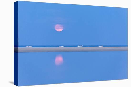 The pink full moon is reflected in the blue water of the Notteri pond, Villasimius, Sardinia, Italy-Roberto Moiola-Stretched Canvas