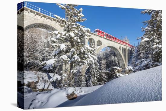 The red train on viaduct surrounded by snowy woods, Cinuos-Chel, Canton of Graubunden, Engadine, Sw-Roberto Moiola-Stretched Canvas