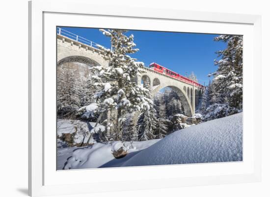 The red train on viaduct surrounded by snowy woods, Cinuos-Chel, Canton of Graubunden, Engadine, Sw-Roberto Moiola-Framed Photographic Print