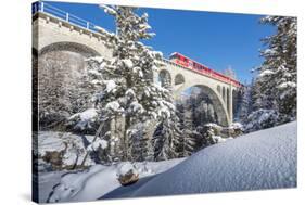 The red train on viaduct surrounded by snowy woods, Cinuos-Chel, Canton of Graubunden, Engadine, Sw-Roberto Moiola-Stretched Canvas