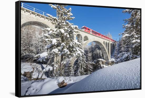 The red train on viaduct surrounded by snowy woods, Cinuos-Chel, Canton of Graubunden, Engadine, Sw-Roberto Moiola-Framed Stretched Canvas