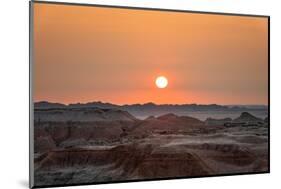 The sun setting over the landscape of hoodoos and hills of Badlands National Park.-Sheila Haddad-Mounted Photographic Print