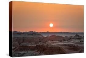 The sun setting over the landscape of hoodoos and hills of Badlands National Park.-Sheila Haddad-Stretched Canvas