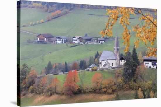 The yellow leaves of a larch frame the alpine church in the fall, St. Magdalena, Funes Valley, Sout-Roberto Moiola-Stretched Canvas