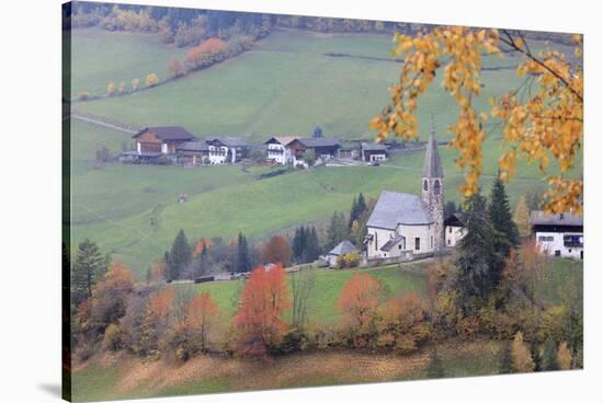 The yellow leaves of a larch frame the alpine church in the fall, St. Magdalena, Funes Valley, Sout-Roberto Moiola-Stretched Canvas