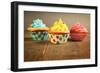 Three Different Colors Cupcakes On A Wooden Table, Blue, Yellow And Pink-pink candy-Framed Art Print