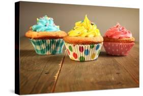 Three Different Colors Cupcakes On A Wooden Table, Blue, Yellow And Pink-pink candy-Stretched Canvas