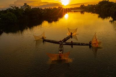 Vietnam. Coordinated lagoon fishing with nets at sunset.