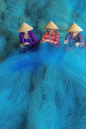 Vietnam. Women repairing fishing nets.
