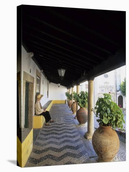 Tourist on Terrace with Striped Cobblestone Floor and Planters, Portugal-Merrill Images-Stretched Canvas