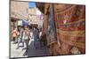 Tourists and Locals Walking Alongside Traditional Rugs in the Medina's Souks-Charlie Harding-Mounted Photographic Print