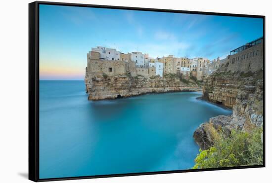 Turquoise sea at sunset framed by the old town perched on the rocks, Polignano a Mare, Province of -Roberto Moiola-Framed Stretched Canvas