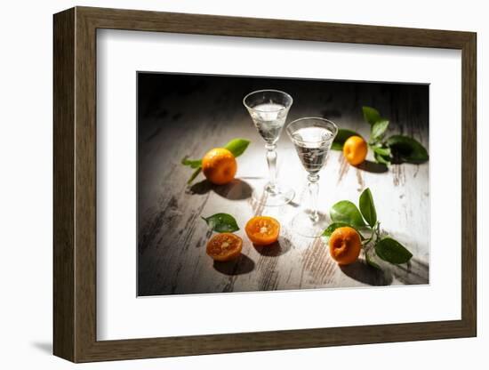 Two Antique Liqueur Glasses with Orange Liqueur and Small Oranges on White Wooden Table-Jana Ihle-Framed Photographic Print