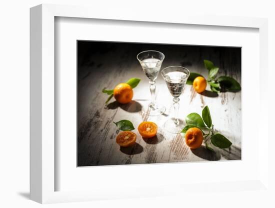 Two Antique Liqueur Glasses with Orange Liqueur and Small Oranges on White Wooden Table-Jana Ihle-Framed Photographic Print