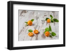 Two Antique Liqueur Glasses with Orange Liqueur and Small Oranges on White Wooden Table-Jana Ihle-Framed Photographic Print
