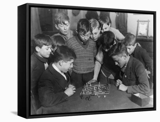 Two Boys Sit for a Game of Chess. Eight Spectators Look On-null-Framed Stretched Canvas