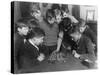Two Boys Sit for a Game of Chess. Eight Spectators Look On-null-Stretched Canvas