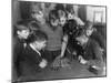 Two Boys Sit for a Game of Chess. Eight Spectators Look On-null-Mounted Photographic Print