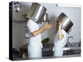 Two Chefs Having Discussion with Large Pans on their Heads-Robert Kneschke-Stretched Canvas