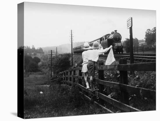 Two Children Stand on a Fence and Wave a Handkerchief at a Passing Steam Train-Staniland Pugh-Stretched Canvas