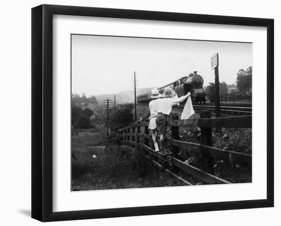 Two Children Stand on a Fence and Wave a Handkerchief at a Passing Steam Train-Staniland Pugh-Framed Photographic Print