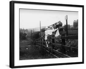 Two Children Stand on a Fence and Wave a Handkerchief at a Passing Steam Train-Staniland Pugh-Framed Photographic Print