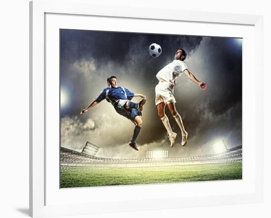 Two Football Players in Jump to Strike the Ball at the Stadium-Sergey Nivens-Framed Photographic Print