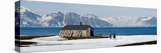 Two Hikers Standing on the Beach Near a Hunting Cabin, Bellsund, Spitsbergen, Svalbard Islands-null-Stretched Canvas