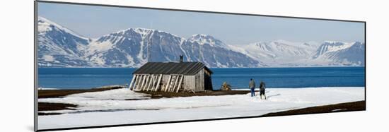 Two Hikers Standing on the Beach Near a Hunting Cabin, Bellsund, Spitsbergen, Svalbard Islands-null-Mounted Photographic Print