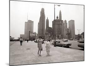 Two Ladies Walking the Sidewalk Skyscrapers in Chicago America's Windy City, in the 1960s-null-Mounted Photographic Print