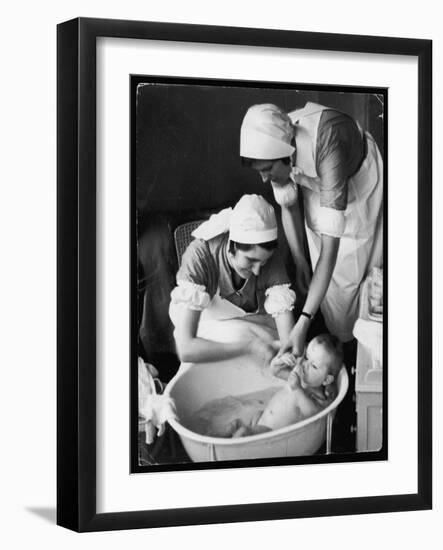 Two Nurses Bath a Baby-null-Framed Art Print