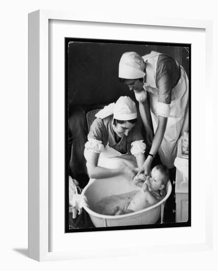 Two Nurses Bath a Baby-null-Framed Art Print