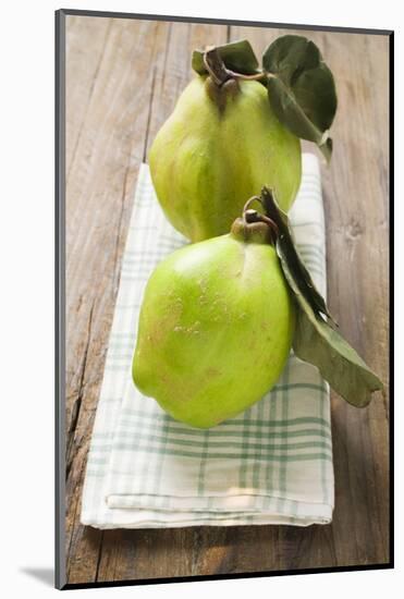 Two Quinces with Leaves on Tea Towel-Eising Studio - Food Photo and Video-Mounted Photographic Print