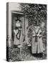 Two Welshwomen in Traditional Dress Stand Outside Their Cottage with a Spinning Wheel-null-Stretched Canvas