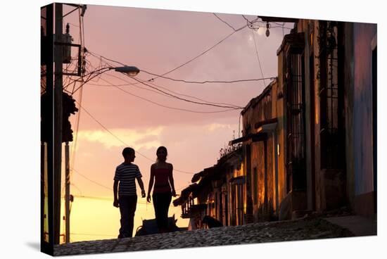 Two Young People in Silhouette at Sunset on Cobbled Street with Colourful Orange Sky Behind-Lee Frost-Stretched Canvas