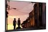Two Young People in Silhouette at Sunset on Cobbled Street with Colourful Orange Sky Behind-Lee Frost-Mounted Photographic Print