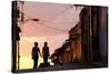 Two Young People in Silhouette at Sunset on Cobbled Street with Colourful Orange Sky Behind-Lee Frost-Stretched Canvas