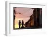 Two Young People in Silhouette at Sunset on Cobbled Street with Colourful Orange Sky Behind-Lee Frost-Framed Photographic Print