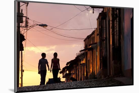 Two Young People in Silhouette at Sunset on Cobbled Street with Colourful Orange Sky Behind-Lee Frost-Mounted Photographic Print