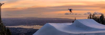 Freestyle skier doing a trick off a jump above city at sunset, Canada, North America-Tyler Lillico-Stretched Canvas