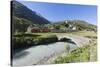 Typical red Swiss train on Hospental Viadukt surrounded by creek and green meadows, Andermatt, Cant-Roberto Moiola-Stretched Canvas