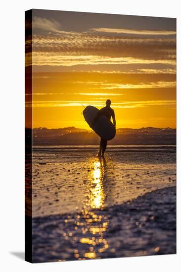 Uk, Cornwall, Polzeath. a Woman Comes in from an Evening Surf Against a Stunning Sunset.-Niels Van Gijn-Stretched Canvas