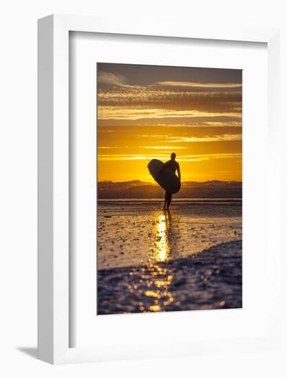 Uk, Cornwall, Polzeath. a Woman Comes in from an Evening Surf Against a Stunning Sunset.-Niels Van Gijn-Framed Photographic Print