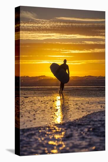 Uk, Cornwall, Polzeath. a Woman Comes in from an Evening Surf Against a Stunning Sunset.-Niels Van Gijn-Stretched Canvas