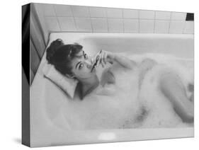 Unexposed Nude Woman in the Bathtub Amid the Bubbles While Smoking a Cigarette-Peter Stackpole-Stretched Canvas