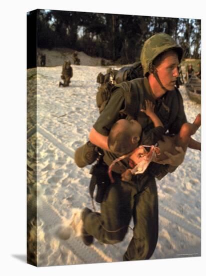 US Marine Medic Running Along Beach with Injured Vietnamese Infant under Fire During Vietnam War-Paul Schutzer-Stretched Canvas